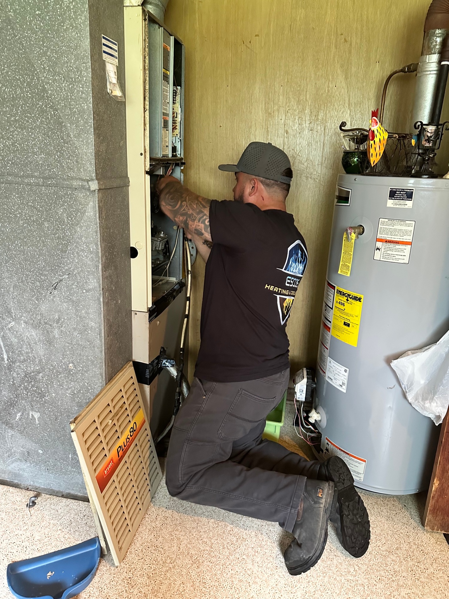 Esco's Heating & Cooling technician servicing a residential furnace and water heater